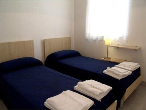 2 camas en una habitación con sábanas azules y toallas blancas en Donnafugata Relais, en Marina di Ragusa