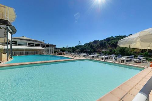 a large swimming pool with chairs and an umbrella at Hotel Le Phoebus Garden & Spa in Gruissan