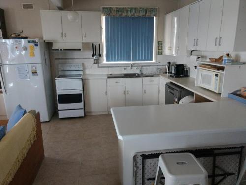 a kitchen with white appliances and a white counter top at Seafront Shack in Port Hughes