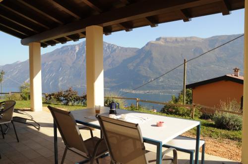un tavolo e sedie su un patio con montagne sullo sfondo di Villetta 56 Blu Yellow and Red Lake view Garden Private Parking by Garda Domus Mea a Tremosine Sul Garda