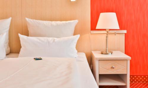 a bedroom with a bed and a lamp on a night stand at Hotel Stadt Kappeln in Kappeln