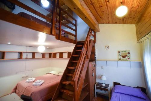 a bedroom with a bunk bed and a wooden staircase at Casa en los troncos Parque Primavesi. in Mar del Plata