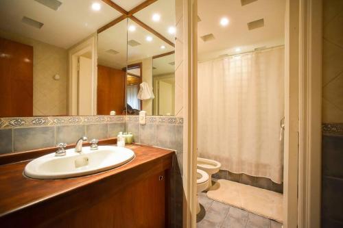 a bathroom with a sink and a toilet and a mirror at Casa en los troncos Parque Primavesi. in Mar del Plata