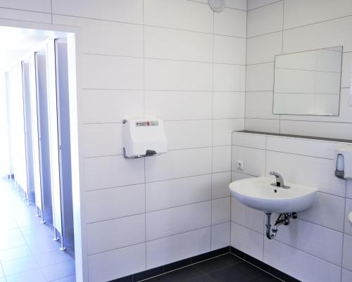 La salle de bains blanche est pourvue d'un lavabo et d'un miroir. dans l'établissement Dünencamping Amrum, à Wittdün