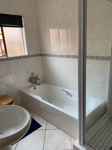 a bathroom with a bath tub and a sink at Celtis Lane Guest House in Boksburg