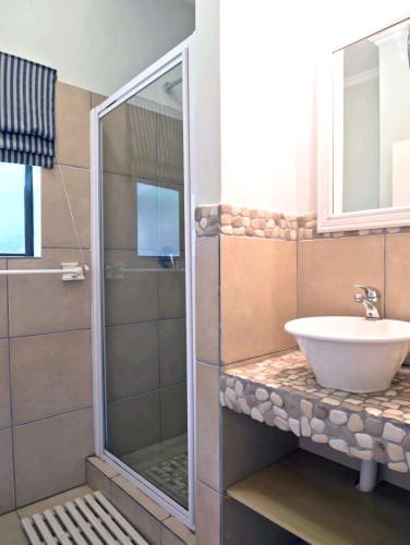 a bathroom with a glass shower and a sink at 6 Margaret in Scottburgh