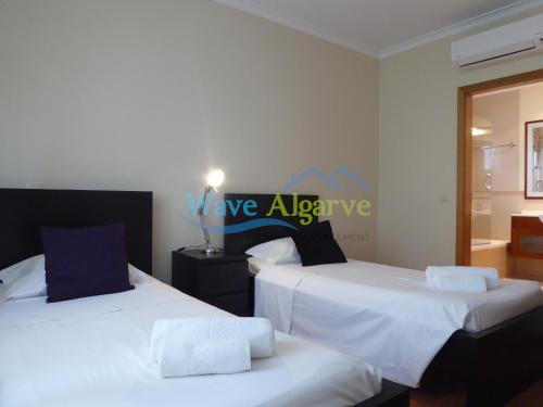 2 Betten in einem Zimmer mit Schild an der Wand in der Unterkunft O Pomar in Cabanas by Wave Algarve in Cabanas de Tavira