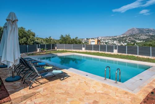 a swimming pool with chairs and an umbrella at Horizon Villa Almyrida in Almyrida