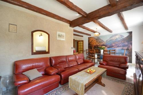 a living room with a leather couch and a table at Villa charmante à Saint-Didier avec piscine privée in Saint-Didier