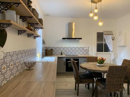 a kitchen with a table and chairs in a kitchen at La grange du bois in Fresnicourt-le-Dolmen