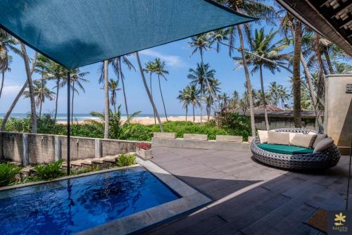 a patio with a swimming pool and palm trees at Rakuen Beach Villa in Hikkaduwa