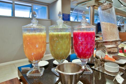 three glass vases filled with different colored liquids on a counter at Transamerica Executive Campos dos Goytacazes in Campos dos Goytacazes