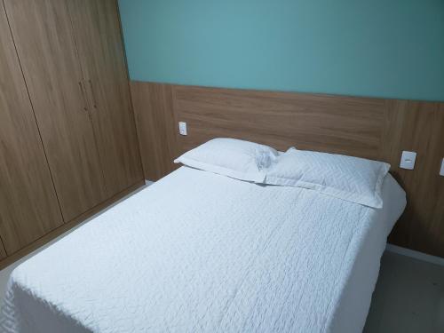 a bedroom with a bed with white sheets and pillows at Guarajuba Cond Paraiso dos Coqueiros in Camaçari