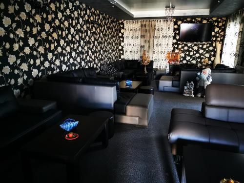 a living room with black leather furniture and wallpaper at Max - Mamaia Nord in Mamaia Nord