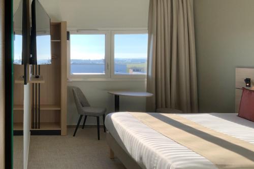 ein Hotelzimmer mit einem Bett, einem Tisch und einem Fenster in der Unterkunft Hôtel Akena Troyes - La Chapelle St-Luc in Troyes