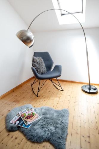 a living room with a chair and a rug and a lamp at Schusterhof-Appartments in Dölsach