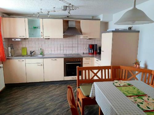 d'une cuisine avec des placards blancs, une table et une table. dans l'établissement Ferienwohnung Riedl, à Klingenthal