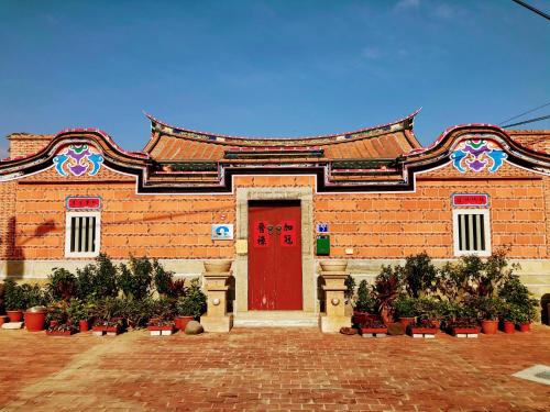 a building with a red door and some plants at 金門后倉七號新古厝民宿 in Jinning