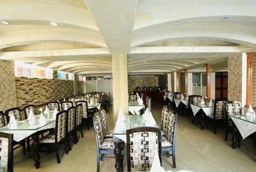 Crown Plaza Residency في سريناغار: غرفة طعام مع طاولات وكراسي في مطعم