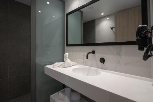 a bathroom with a white sink and a mirror at NM Apartments in Mastichari