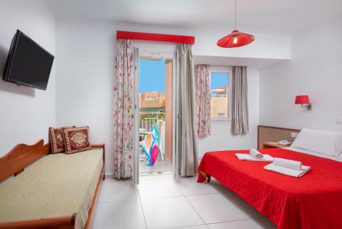 a bedroom with two beds and a red bedspread at Bellos Hotel Apartments in Hersonissos