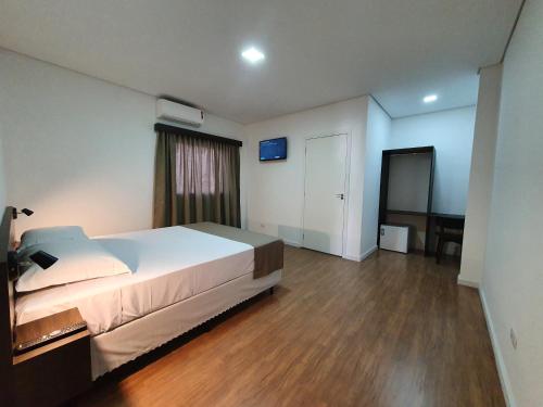 a bedroom with a bed and a desk in it at Hotel Carmelo in São José dos Pinhais