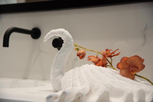 a towel swan sitting on a sink with flowers at NM Apartments in Mastichari