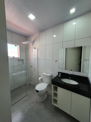 a bathroom with a toilet and a sink and a mirror at Hotel Carmelo in São José dos Pinhais