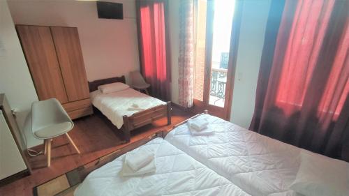 a bedroom with two beds and a chair and a window at Diporto in Chania Town