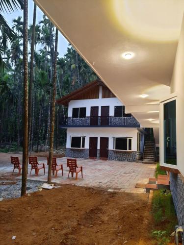 a building with red chairs in front of it at Hosamane Farm Inn in Sringeri