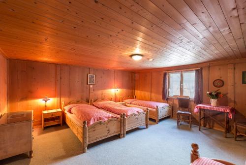 Schlafzimmer mit 3 Betten und Holzdecke in der Unterkunft Cresta - 9,5-Zimmerhaus für 19 - 20 Personen, 270m2 in Conters