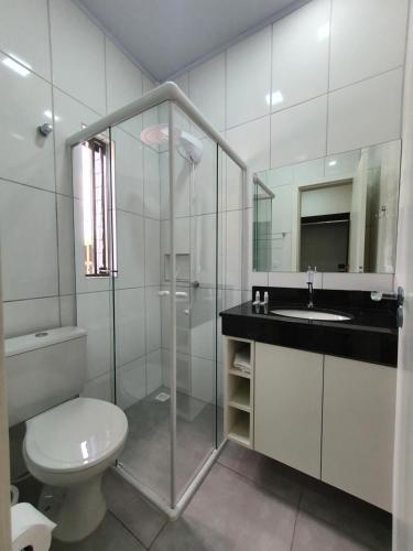 a white bathroom with a toilet and a sink at Hotel Carmelo in São José dos Pinhais