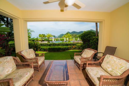 a screened in porch with wicker furniture and a large window at Del Mar 3N 3 bdr Garden View in Los Suenos in Herradura