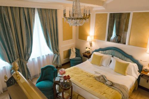 a bedroom with a bed and a chair and a chandelier at Hotel Bernini Palace in Florence