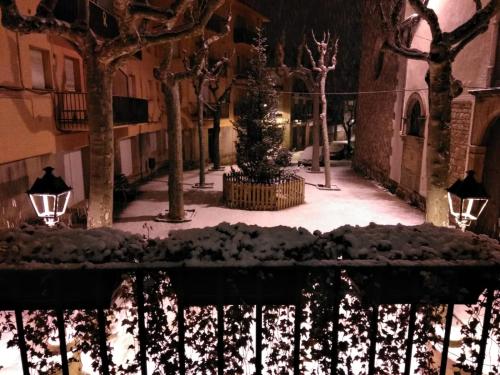 uma rua nevada à noite com uma árvore de Natal em Escloper B&B em Sant Juliá de Vilatorta