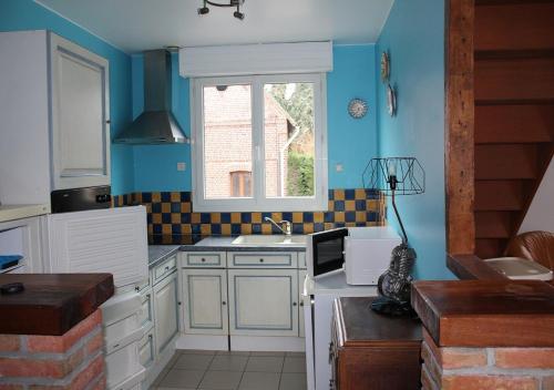 d'une cuisine aux murs bleus et d'une fenêtre. dans l'établissement La Ferme de la Croix, à Saint-Quentin-Lamotte-Croix-au-Bailly