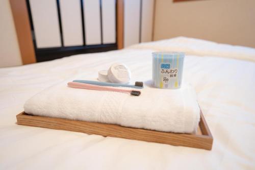 a wooden tray with a toothbrush and a cup on a bed at 大吉屋本館 ワンフロア貸切部屋 名駅離れ in Nagoya