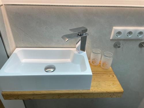 a white sink in a bathroom with two glasses at Landhaus Kössel in Füssen