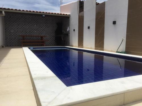 uma piscina com piso de azulejo azul e uma casa em Casa PRAIA DE CARAPIBUS PB- TEMPORADA em João Pessoa