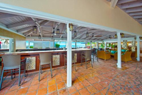 a bar in a restaurant with tables and chairs at Pineapple Beach Club - All Inclusive - Adults Only in Willikies