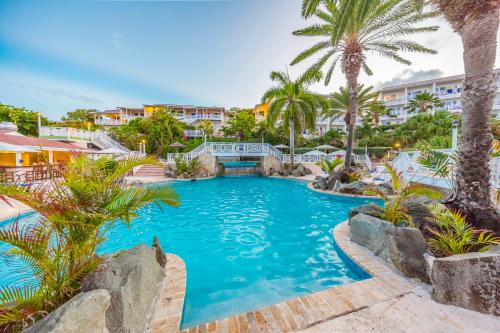 a pool at a resort with palm trees and buildings at Pineapple Beach Club - All Inclusive - Adults Only in Willikies