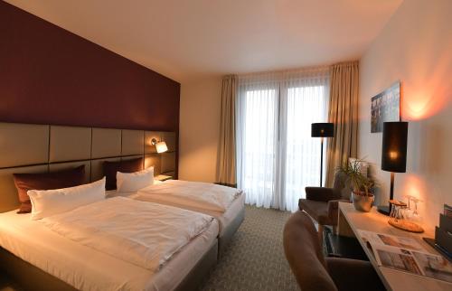 a hotel room with a large bed and a desk at Landhotel Rittmeister & Kräuter-SPA Adults Only in Rostock