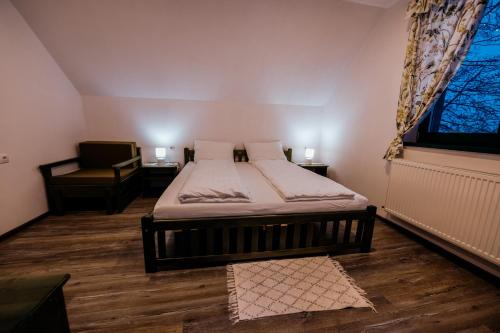 a bedroom with a bed and a chair and a window at Kádárház in Vlăhiţa