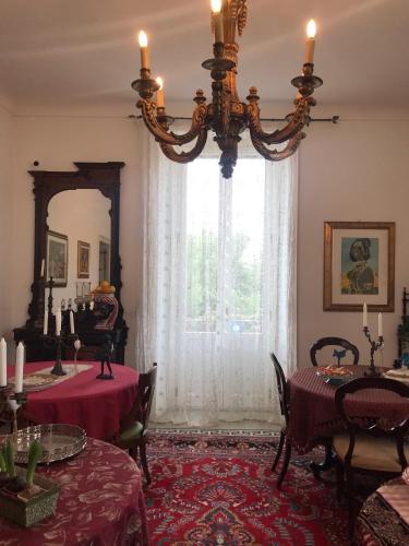 un comedor con 2 mesas y una lámpara de araña en B&B Nike - Rooms Only, en Siracusa