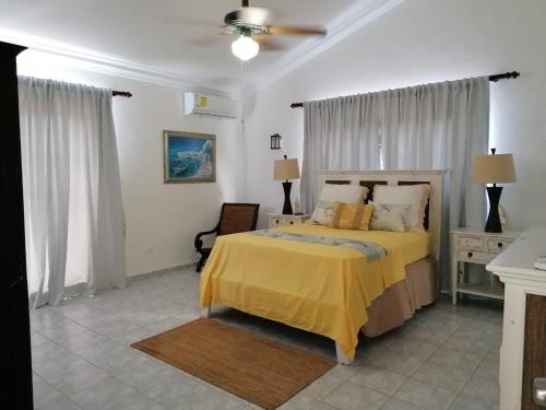 1 dormitorio con 1 cama con colcha amarilla en Villas Del Jardin 7, en Juan Dolio