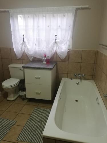 a bathroom with a tub and a toilet and a window at A-Cody Place in Louis Trichardt