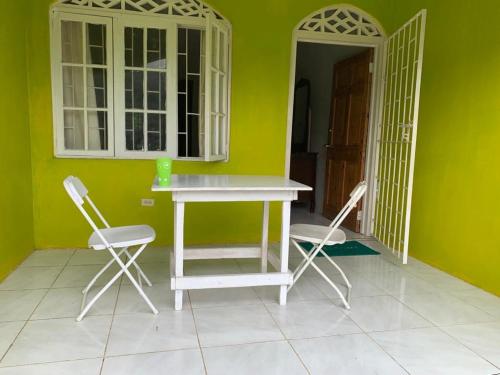 una mesa y sillas en una habitación con una pared verde en ThA LaGooN SpOt Caribbean BrEeZe, en Port Antonio