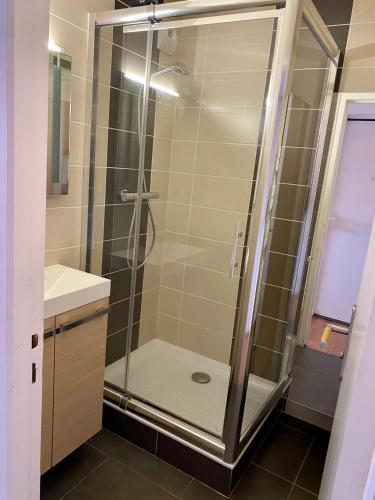 une douche avec une porte vitrée dans une salle de bain dans l'établissement T2 face à la mer, à Sète