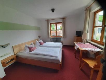 a bedroom with two beds and a table and windows at Gasthof Rundeck 