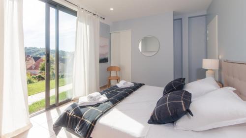 a bedroom with a bed with pillows and a large window at 100% Relax avec Jacuzzi Privatif in Sarlat-la-Canéda